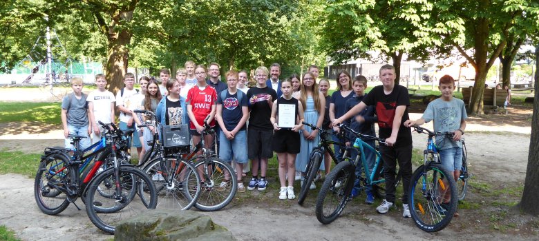 Schulleiter Sebastian Menke und Klassenlehrerin Ruth Buckebrede nahmen gemeinsam mit den Schülerinnen und Schülern der 7b Urkunde und Eisgutschein von Bürgermeister Marco Diethelm und Klimaschutzmanagerin Caroline Hüttemann entgegen