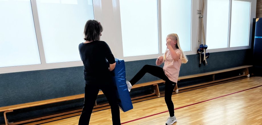 ein Mädchen mit Trainerin in Turnhalle